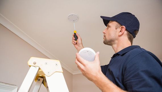 guy fitting fire alarm in office